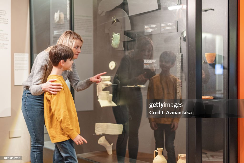A Caucasian Mom Showing Artefacts To Her Son And Educating Him On History While They Are Visiting a History Museum