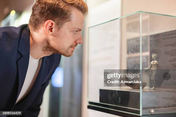 interessierter erwachsener kaukasischer männlicher museumsangestellter, der sich über die neuzugänge im museum informiert - museumswärter stock-fotos und bilder