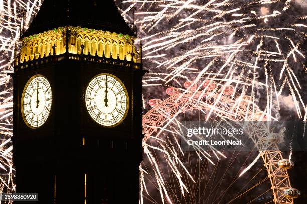 The clock strikes midnight on the face of Queen Elizabeth Tower, commonly known as Big Ben, as fireworks erupt from the London Eye on January 01,...