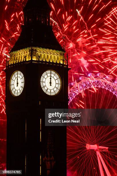 The clock strikes midnight on the face of Queen Elizabeth Tower, commonly known as Big Ben, as fireworks erupt from the London Eye on January 01,...