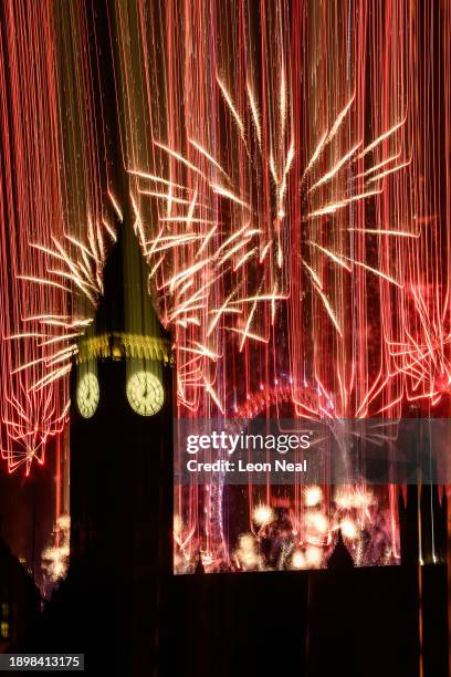 In this long exposure, Queen Elizabeth Tower, commonly known as Big Ben, is seen as as fireworks erupt from the London Eye on January 01, 2024 in...