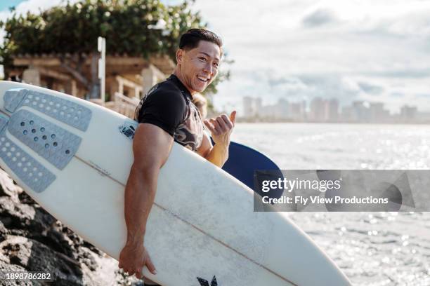 surfista masculino multirracial haciendo el signo de shaka - surfers fotografías e imágenes de stock