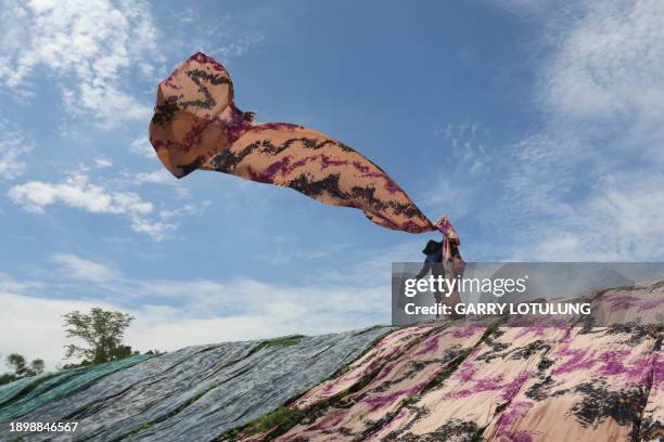 Worker arranges fabric known locally as "beach fabric", used to make Muslim women's garments, to dry on a riverbank in Surakarta, Central Java, on...