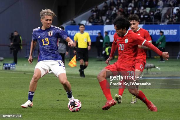 Keito Nakamura of Japan and Santipharp Channgom of Thailand compete for the ball during the international friendly match between Japan and Thailand...