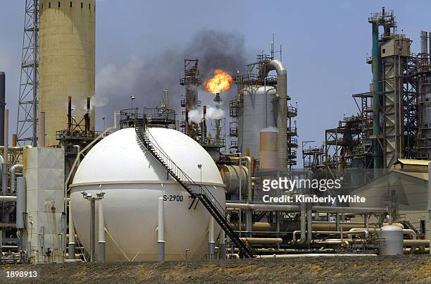 Controlled flame burns behind a storage tank in the oil refinery complex of Amuay-Cardon April 4, 2003 in Paraguana, located about 350 miles West of...