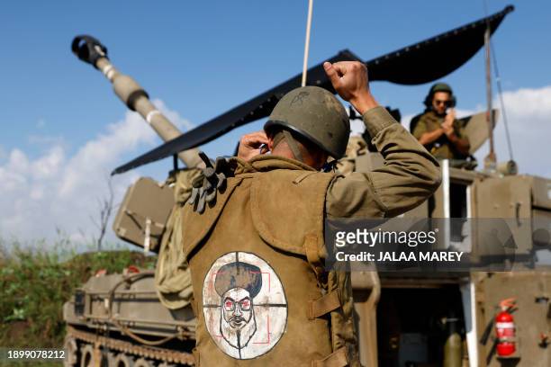 An Israeli soldier wearing a patch on the back of his flack jacket showing Lebanon's Hezbollah leader Hassan Nasrallah as a target, stands in front...