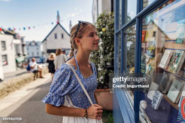 teenager-mädchen schaut sich buchhandlung in lyme regis, dorset, vereinigtes königreich an - schaufenster stock-fotos und bilder