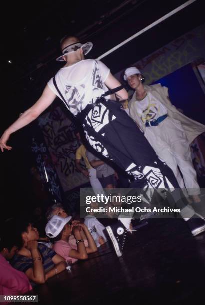 Rear view of a fashion model wearing a white t-shirt with black abstract motifs, black trousers with white abstract motifs, on the runway at the...