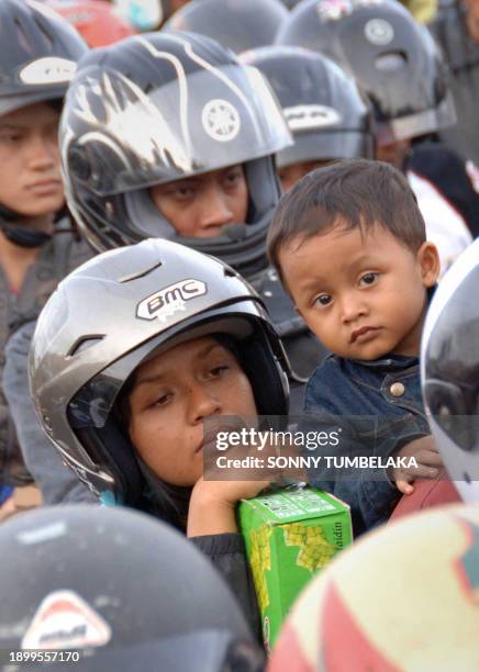 Woman waits with her child as hundreds of people on motorcycles arrive at the ferry terminal in Gilimanuk port, on the island of Bali to catch a...