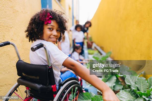 portrait of a girl student using wheelchair its doing gardening at school - its a girl stockfoto's en -beelden