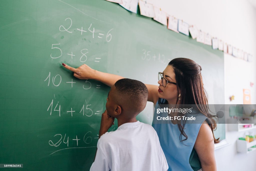 Lehrer, der den Schüler im Klassenzimmer in der Schule unterrichtet