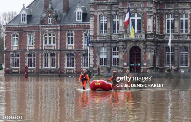 Firefighters evacuate a resident with an inflatable boat in the town hall square of flooded Arques, northern France, on January 4 following the...