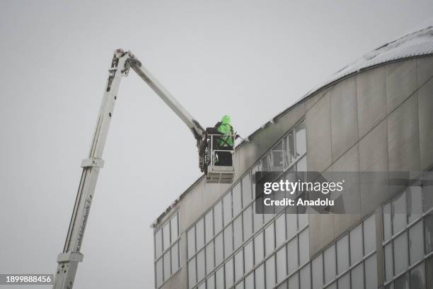 Workers clean snow from the rooftop of Kiasma museum during a snowy day as they continue their daily life on a cold weather in Helsinki, Finland on...