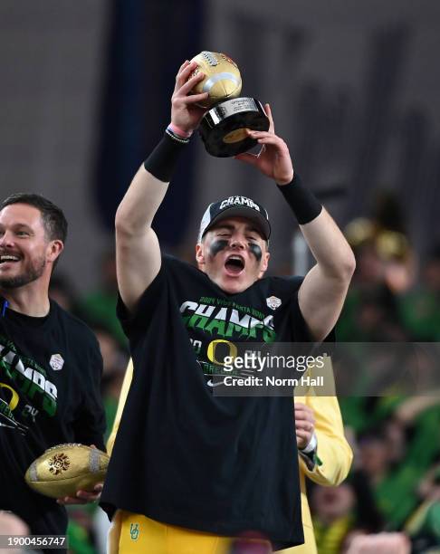Bo Nix of the Oregon Ducks holds up the offensive MVP trophy after beating the Liberty Flames 45-6 in the 2023 Vrbo Fiesta Bowl game at State Farm...