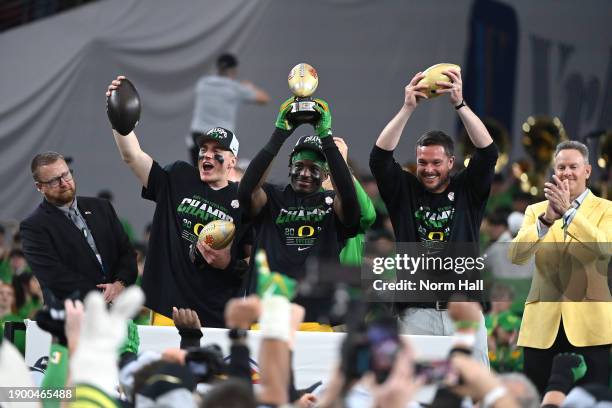 Bo Nix of the Oregon Ducks holds up the offensive MVP trophy, Jeffrey Bassa holds up the defensive MVP trophy and head coach Dan Lanning holds up the...