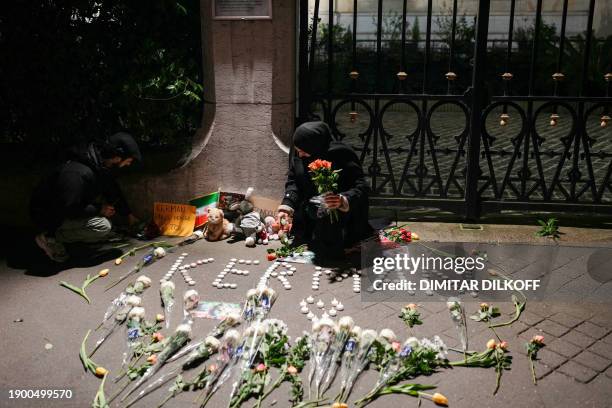 Woman holds flowers during a gathering in tribute to victims in front of the Iranian Embassy in Paris on January 4, 2024 after twin bombings killed...