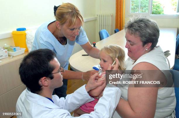 Céline, 2 ans et demi, assise sur les genoux de sa mère, se fait vacciner, le 12 juin 2006 à Dieppe, dans le cadre d'une campagne de vaccination sans...