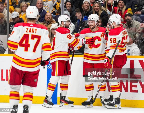 Rasmus Andersson celebrates his goal with Nazem Kadri and MacKenzie Weegar of the Calgary Flames against the Nashville Predators during an NHL game...