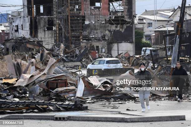 People walk past the burned Wajima Asa-ichi, or morning market area, in the city of Wajima, Ishikawa prefecture, on January 5 after a major 7.5...