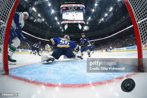 Jordan Binnington of the St. Louis Blues allows a goal as Mark Friedman of the Vancouver Canucks watches in the first period at Enterprise Center on...