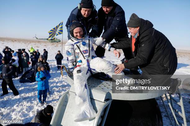 Ground personnel help Russian cosmonaut Sergey Ryazanskiy to get out of the Soyuz MS-05 space capsule after landing in a remote area outside the town...