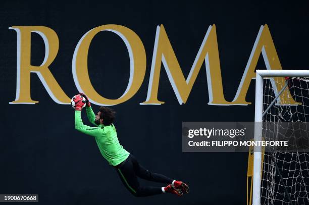 Roma's goalkeeper from Brazil Alisson dives to make a save during a training session on the eve of the Champion's League football match Atletico...