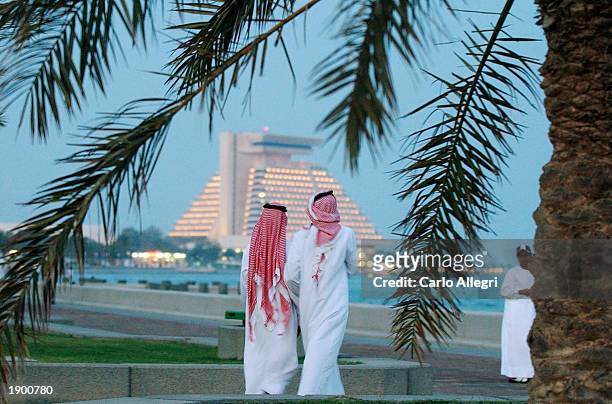 Qatari men walk along the sea wall on the corniche on their way to the evening call to prayer April 6, 2003 in the coastal town of Doha, Qatar. Even...
