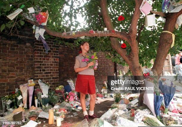 Young girl stands amid a huge array of different kind of tributes, many attached to a tree near the entrance to Kensington Palace 03 September as...