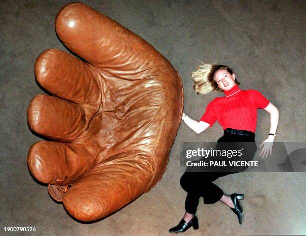 Sotheby's auctioneers assistant Patricia O'Connor wears a giant baseball sofa glove 23 October, which will be auctioned 29 October at their "Design...