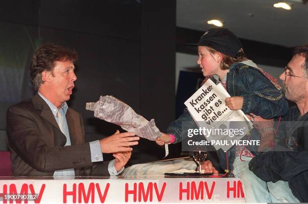 Ex-Beatles bass player Sir Paul McCartney reacts as he is given flowers 16 October by eight-year-old Elvira Suessmeier from Munich, Germany after...