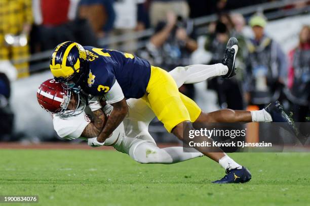 Jermaine Burton of the Alabama Crimson Tide runs with the ball while being tackled by Keon Sabb of the Michigan Wolverines in the fourth quarter...