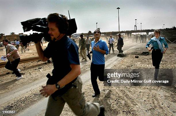 British Channel 4 TV cameraman Tim Lambon and reporter Lindsey Hilsum , run for safety after planes were heard near a destroyed U.S. Tank April 4,...