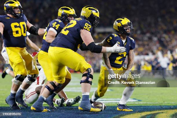 Blake Corum of the Michigan Wolverines celebrates with teammates after scoring a touchdown in overtime against the Alabama Crimson Tide during the...