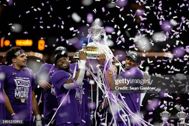 Michael Penix Jr. #9 of the Washington Huskies and Edefuan Ulofoshio celebrate with the trophy after a 37-31 victory against the Texas Longhorns in...
