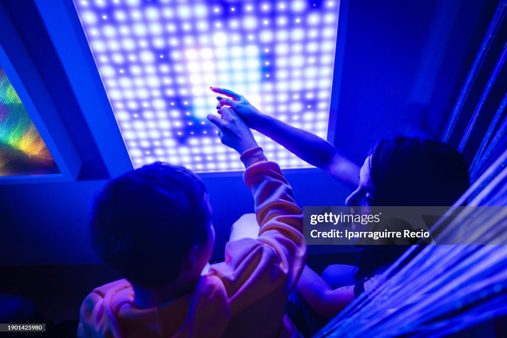 Therapist and young disabled man in a sensory experimental modern room