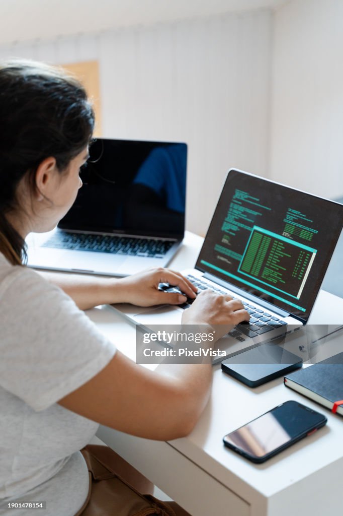Side view of woman working on laptop computer at home.
