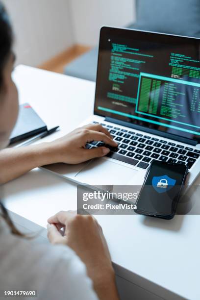 side view of female programmer working on laptop and coding on mobile phone - table font view stock pictures, royalty-free photos & images