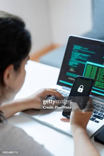 woman using mobile phone and laptop computer at home. cyber security concept. - internet security stock pictures, royalty-free photos & images