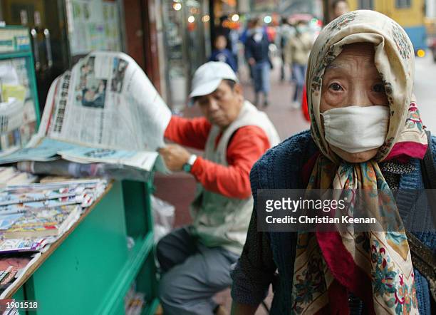 Chinese lady wearing mask to protect from SARS . The government today announced an increase to 883 persons infected with Atypical Pneumonia. Total...