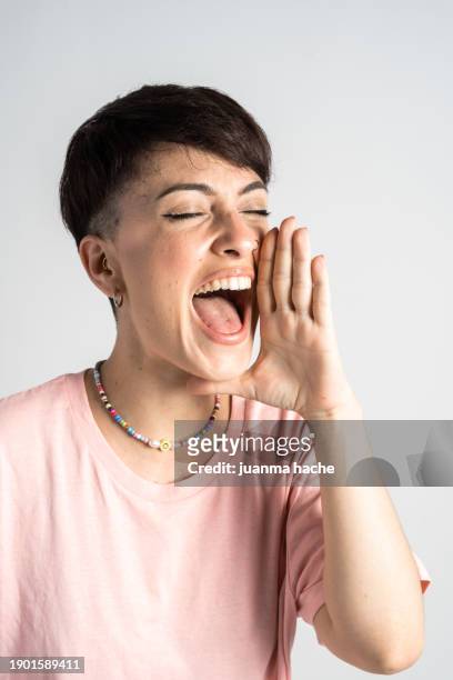 young woman yawning and covering her mouth with hand on white background - hand covering face stock pictures, royalty-free photos & images