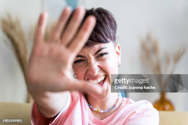 playful woman sitting on sofa at home. - hand showing stockfoto's en -beelden