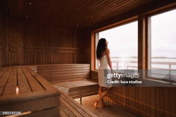woman enjoying the view from a dry sauna - sauna stockfoto's en -beelden