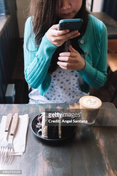 woman snaps a picture of her coffee and cake at a cozy cafe - cozy stock pictures, royalty-free photos & images