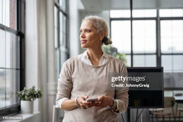 contemplative businesswoman pausing from text messaging - introspeção imagens e fotografias de stock