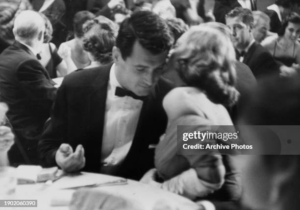 American actor Rock Hudson, wearing a tuxedo and bow tie, in conversation with American actress Tallulah Bankhead at the gala party that followed the...