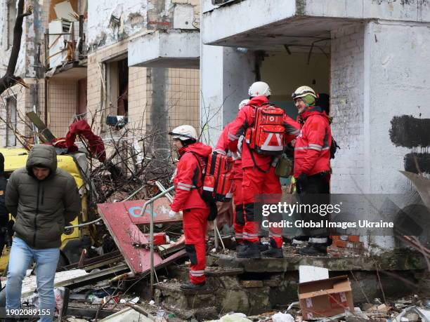 Members of rapid response team of the Red Cross of Ukraine stand amid debris on a porch of a residential building damaged by Russian shelling on...