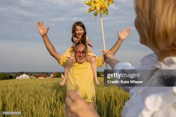 adult mature parents with a cute girl having fun together in the meadow - somme stock pictures, royalty-free photos & images