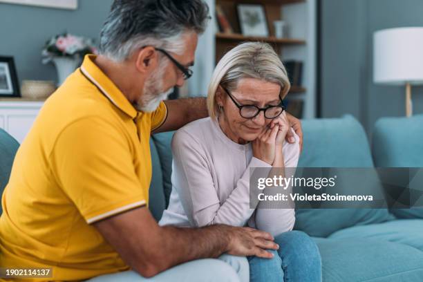 worried couple talking together in the living room at home. - sad husband stock pictures, royalty-free photos & images