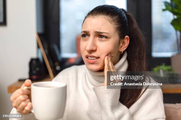 woman drinking coffee feeling tooth pain from teeth sensitivity - cerrar os dentes - fotografias e filmes do acervo