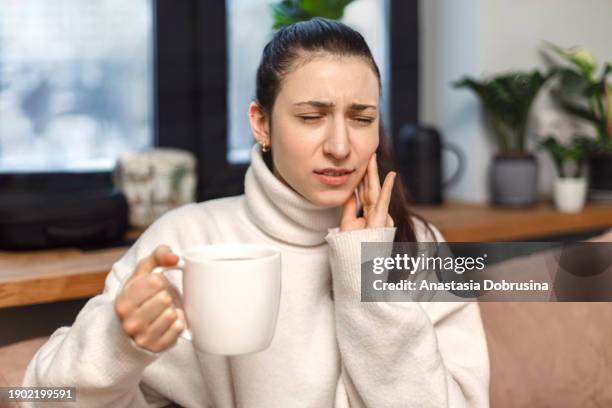 woman with acute toothache holding her cheek. reaction to hot drinks - clenching teeth stock pictures, royalty-free photos & images
